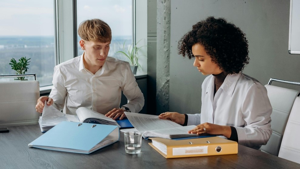 Two people reviewing binders
